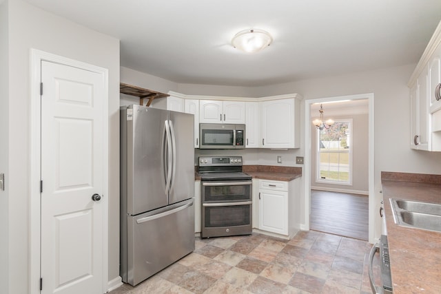 kitchen featuring sink, light wood-type flooring, white cabinetry, a chandelier, and appliances with stainless steel finishes