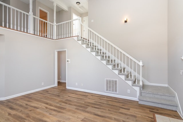 staircase featuring a high ceiling and wood-type flooring