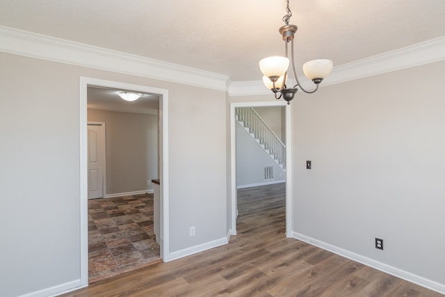 spare room with crown molding, dark hardwood / wood-style floors, and a chandelier