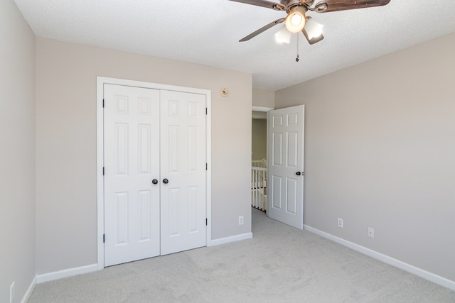 unfurnished bedroom featuring a closet, ceiling fan, light carpet, and a textured ceiling