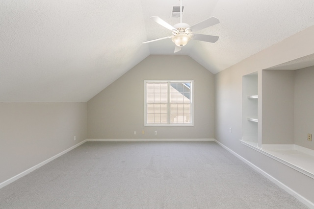 bonus room with ceiling fan, a textured ceiling, vaulted ceiling, and light colored carpet