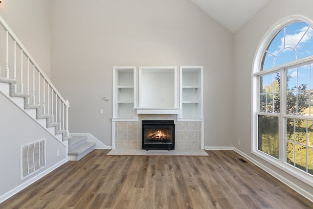 unfurnished living room featuring high vaulted ceiling, a fireplace, and dark hardwood / wood-style flooring