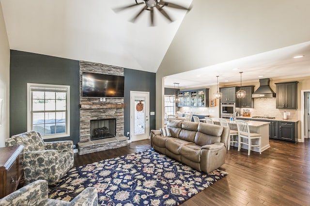 living room featuring dark hardwood / wood-style floors, high vaulted ceiling, a fireplace, and ceiling fan