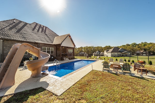 view of pool with a water slide, a yard, and a patio