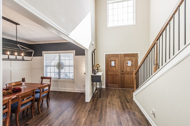 foyer entrance featuring an inviting chandelier, crown molding, a high ceiling, and dark hardwood / wood-style flooring