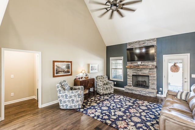 living room with dark wood-type flooring, ceiling fan, high vaulted ceiling, and a stone fireplace