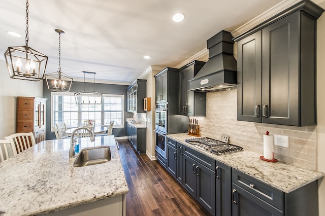 kitchen featuring sink, dark hardwood / wood-style flooring, pendant lighting, stainless steel gas stovetop, and custom range hood