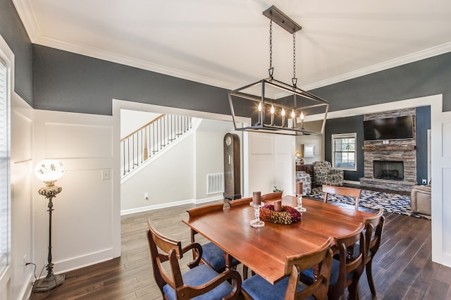 dining space featuring crown molding, dark wood-type flooring, and a fireplace