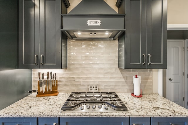 kitchen featuring blue cabinets, stainless steel gas stovetop, light stone counters, and backsplash