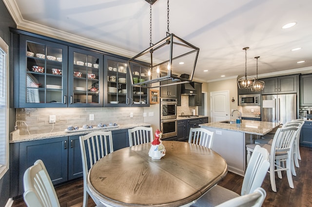 dining space with dark wood-type flooring, a notable chandelier, ornamental molding, and sink