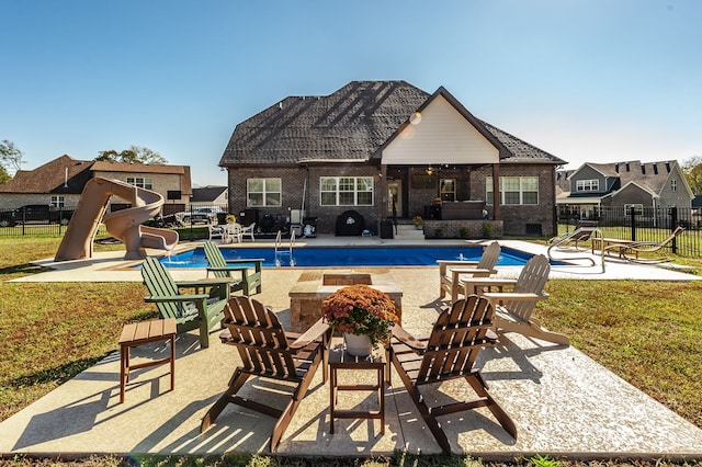 view of swimming pool featuring a patio, a water slide, and a lawn