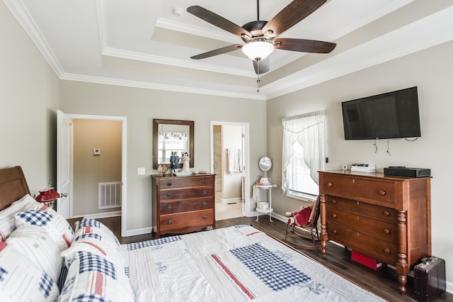 bedroom featuring a raised ceiling, ceiling fan, ensuite bathroom, dark wood-type flooring, and crown molding