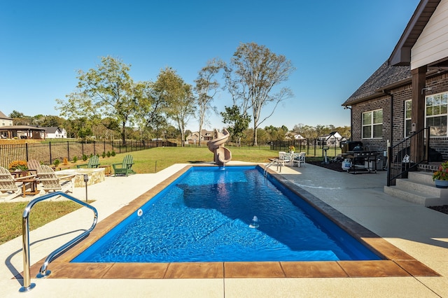 view of pool featuring a patio area, a water slide, and a yard