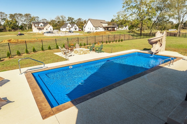 view of pool with a patio, a water slide, a lawn, and a fire pit