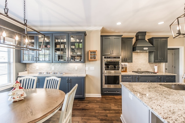 kitchen with light stone countertops, sink, hanging light fixtures, custom exhaust hood, and dark wood-type flooring