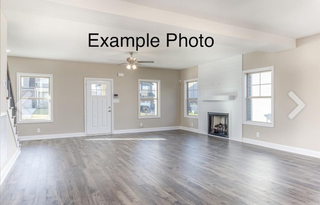 unfurnished living room featuring dark wood-type flooring and ceiling fan