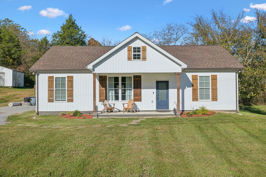 rear view of property featuring a yard and a porch