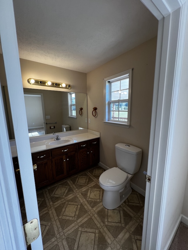 bathroom with vanity, toilet, and a textured ceiling