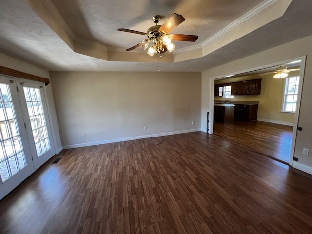 unfurnished living room featuring dark wood-type flooring, a tray ceiling, and plenty of natural light