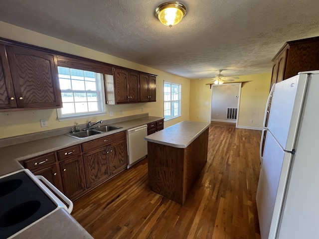 kitchen with white appliances, a healthy amount of sunlight, sink, a center island, and dark hardwood / wood-style floors