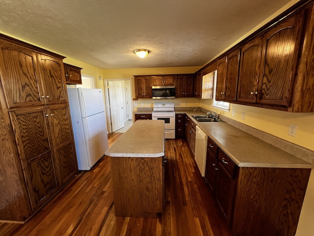 kitchen featuring sink, a textured ceiling, white appliances, and dark hardwood / wood-style flooring