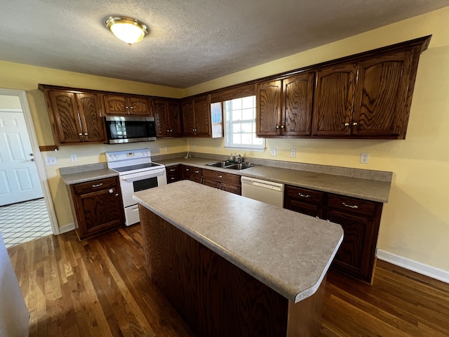 kitchen with white appliances, sink, a textured ceiling, dark brown cabinets, and dark hardwood / wood-style flooring