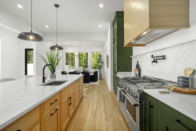 kitchen featuring light hardwood / wood-style flooring, range with two ovens, sink, light stone countertops, and pendant lighting