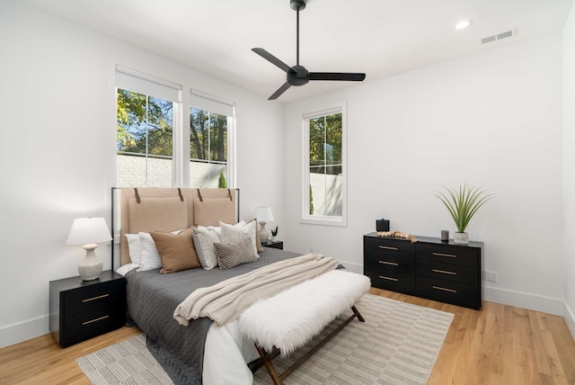 bedroom with ceiling fan, multiple windows, and light wood-type flooring