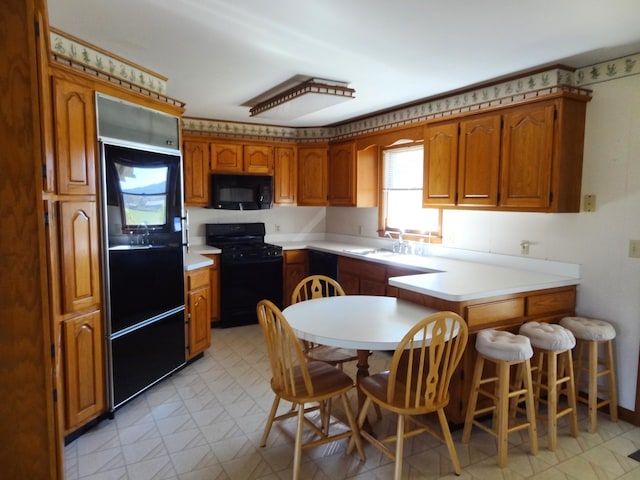 kitchen featuring sink, black appliances, and a kitchen bar