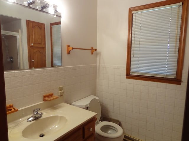 bathroom with toilet, walk in shower, vanity, and tile walls