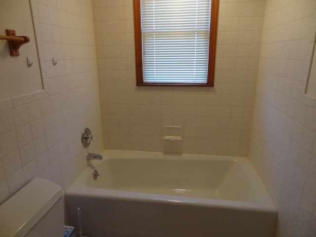 bathroom with a bath, toilet, and tile walls