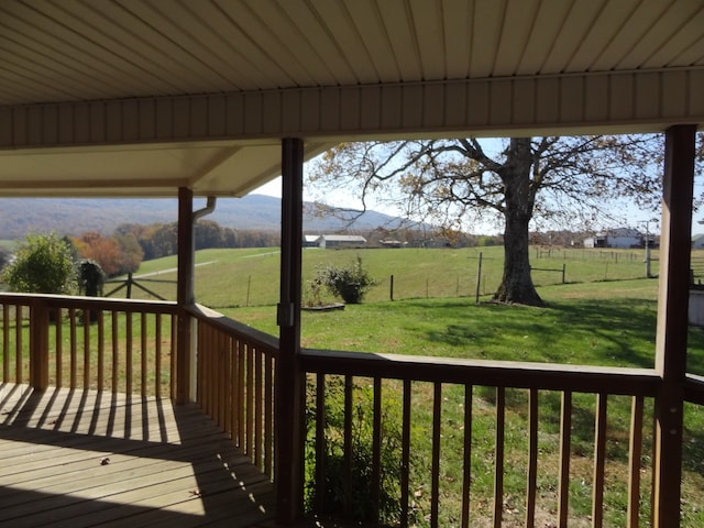 wooden deck with a rural view, a yard, and a mountain view