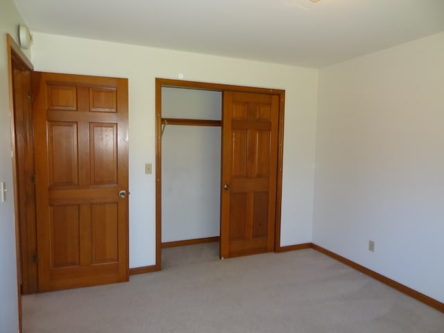 unfurnished bedroom with a closet and light colored carpet