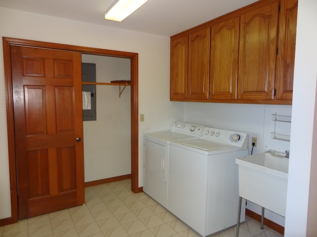 washroom with sink, electric panel, washing machine and dryer, and cabinets