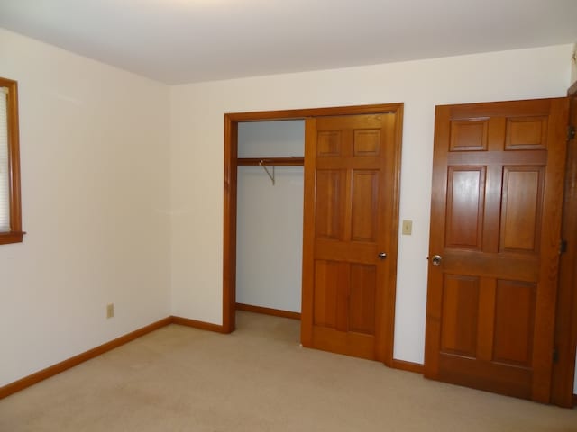 unfurnished bedroom featuring a closet and light colored carpet