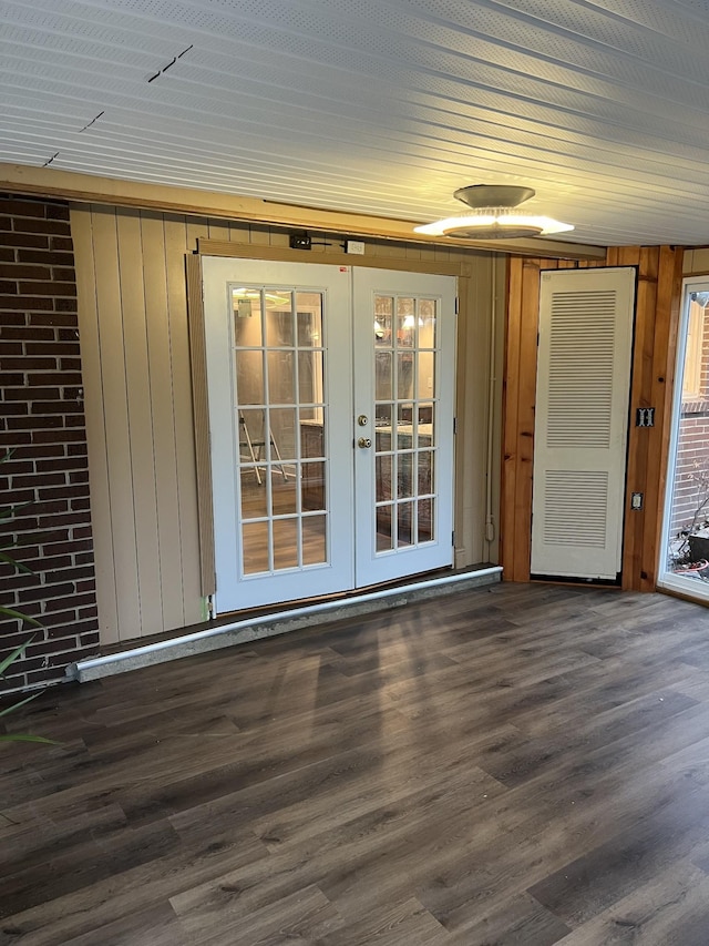 unfurnished room featuring dark wood-type flooring, french doors, and wooden walls