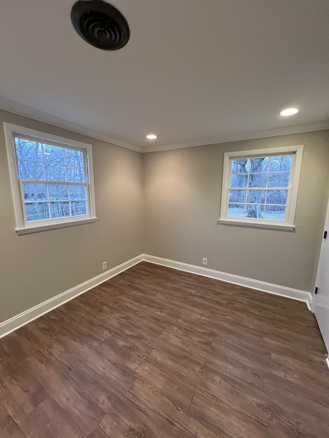 empty room featuring crown molding, dark wood-type flooring, and plenty of natural light