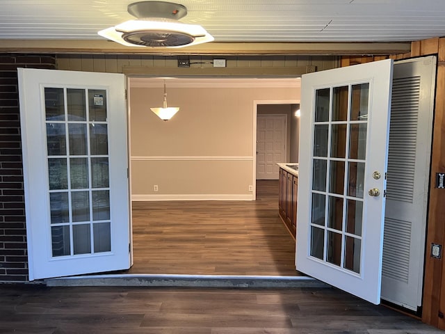 doorway featuring crown molding and dark wood-type flooring