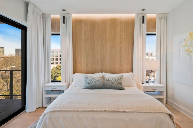 bedroom with access to exterior, light wood-type flooring, and multiple windows