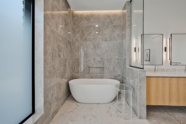 bathroom with tile patterned flooring, vanity, a tub, and tile walls