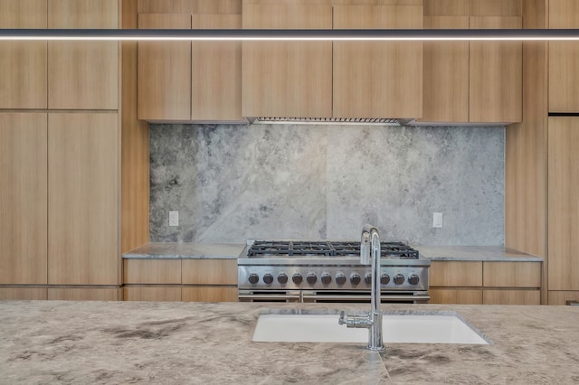 kitchen featuring gas stove, backsplash, and light stone countertops