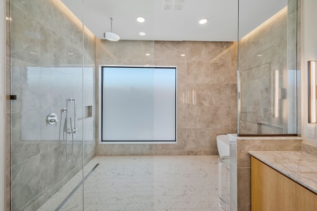 bathroom with a shower, vanity, and tile walls