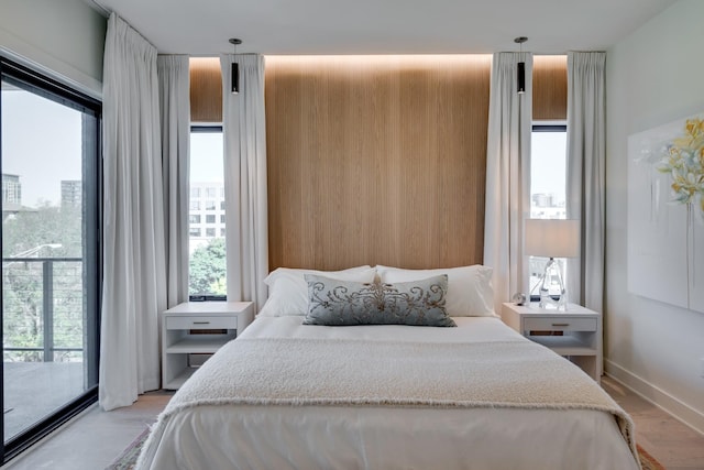 bedroom featuring access to exterior, light hardwood / wood-style flooring, and multiple windows