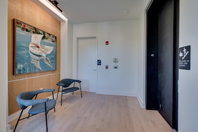 corridor with light hardwood / wood-style flooring and wooden walls