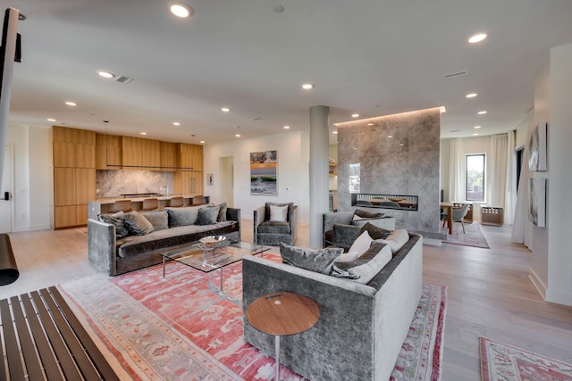 living room with a tile fireplace and light wood-type flooring