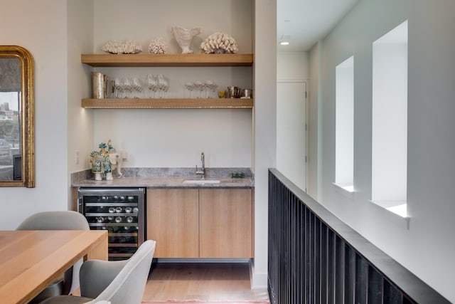 bar with hardwood / wood-style flooring, light brown cabinetry, sink, and wine cooler