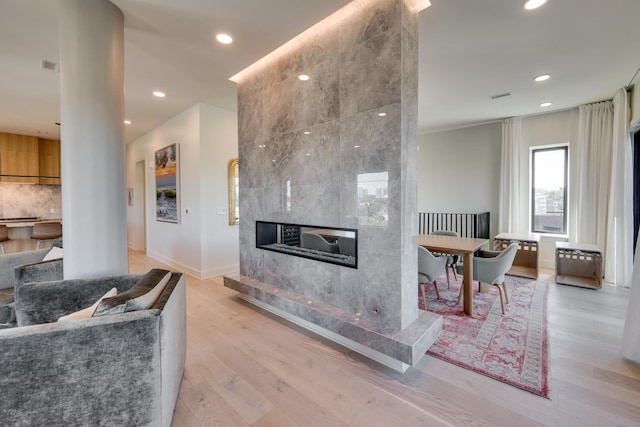 interior space featuring tasteful backsplash, a tile fireplace, and light hardwood / wood-style floors