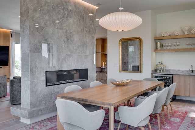 dining space featuring wine cooler, sink, tile walls, and a tile fireplace