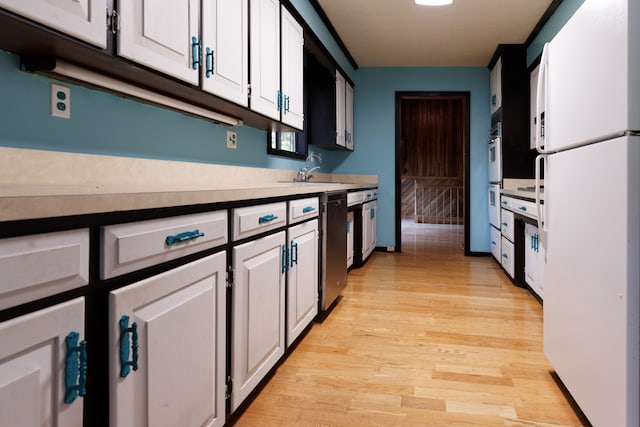 kitchen with white appliances, white cabinetry, light hardwood / wood-style flooring, and sink