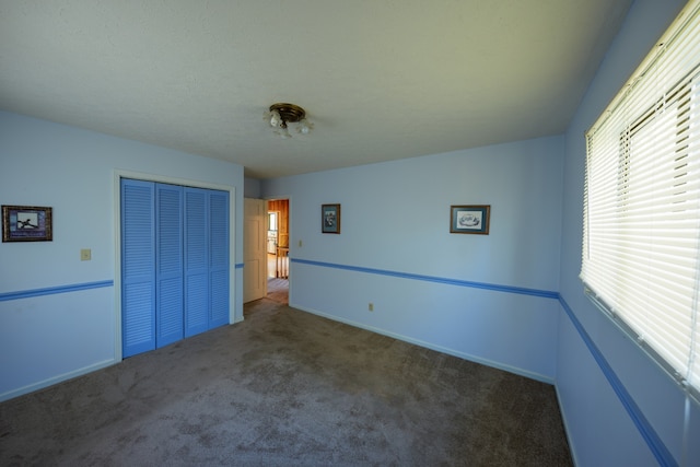 unfurnished bedroom featuring dark carpet and a closet